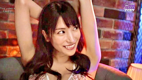 Japanese beauty in sheer lace bra lifts arms smiling seductively on couch