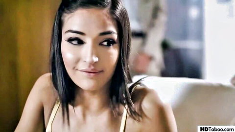 Brunette teen with almond eyes smiling seductively in yellow tank top showing cleavage