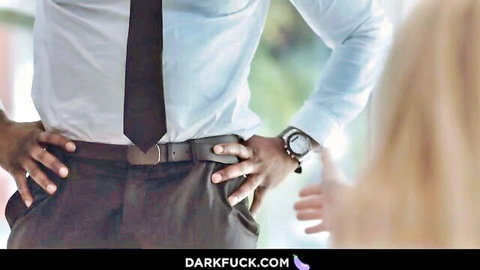 Suited black man stands hands on belt teasing petite blonde woman from behind