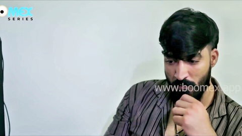 Handsome young Asian man with thick mustache and beard posing thoughtfully in striped shirt