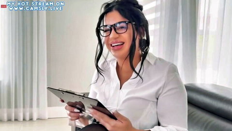 Curvy brunette in glasses smiles with clipboard in white blouse