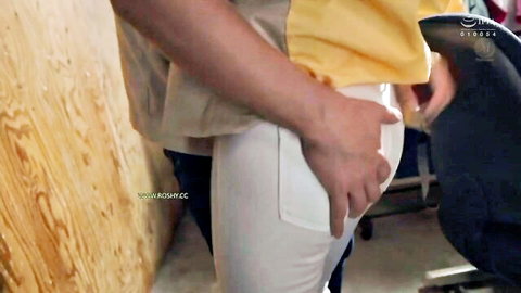 Man gropes woman's tight white pants-covered ass from behind in office