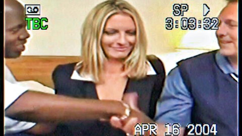 Blonde woman in suit shakes hands with black man beside white man, 2004