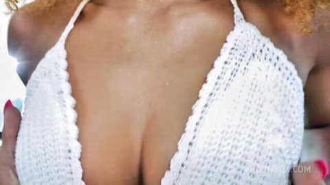 Tanned busty babe in white crochet bikini top squeezing deep cleavage