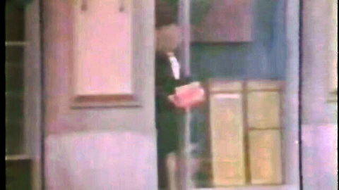 Vintage suited man holding red folder in wooden paneled room doorway