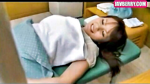 Smiling Asian woman in white top and blue skirt lying relaxed in JAV video