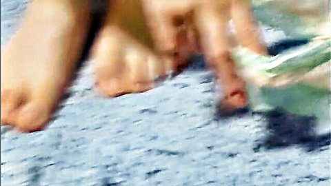 Blurry closeup of bare feet, toes, and hands with cash, foot fetish tease