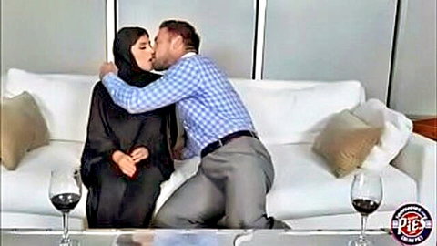 Muslim woman in hijab passionately kissing suited white man