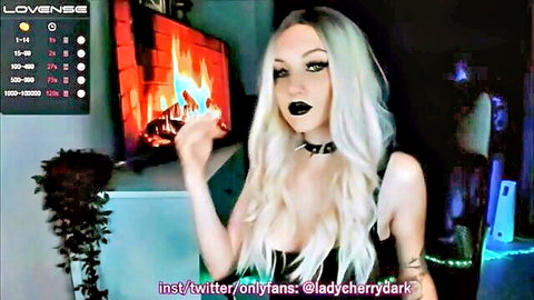 Goth babe Lady Cherry Dark teases massive cleavage tits on webcam with fireplace glow