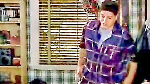 Young man in plaid shirt standing casually in indoor setting