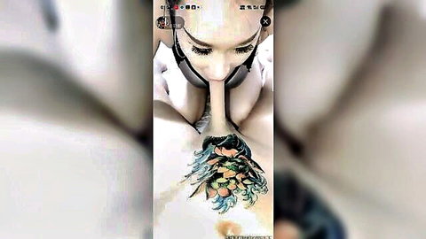 Asian woman with colorful chest tattoo giving close-up blowjob, eyes gazing up