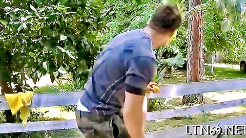 Man bending over with pants and underwear down exposing bare ass outdoors near fence