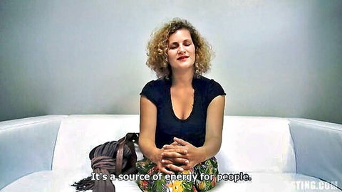Curly haired amateur in black top and floral pants at casting, smiling relaxed