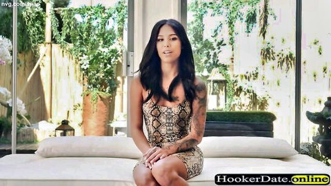 Tattooed Asian babe in tight snakeskin mini dress teasing seductively on white couch