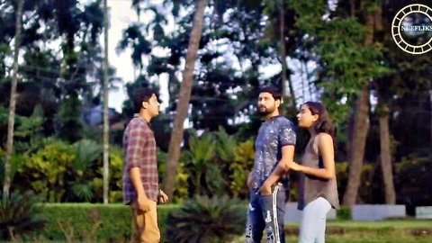 South Asian brunette woman stands with two men in tropical park wearing casual clothes