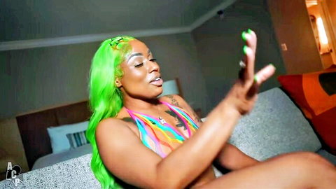 Curvy Black woman with green wig in colorful bikini, teasing seductively in clown-themed adult video