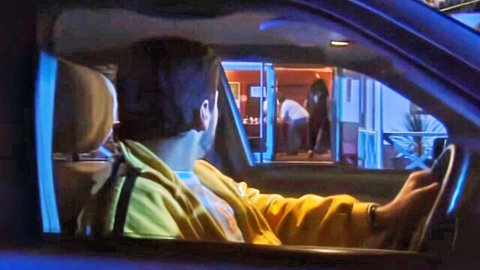 Man in yellow hoodie driving car, peeking at club scene outside in Cape Town night