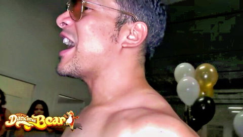 Dancing Bear: Shirtless Latino muscular man grinning at party, women watching action
