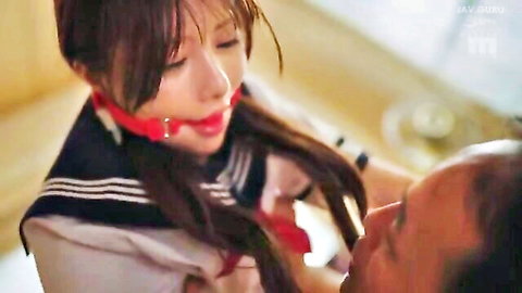 Bound Japanese schoolgirl in sailor uniform with red ball gag in intimate BDSM scene
