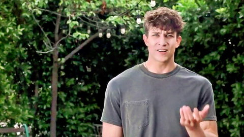 Handsome young white guy gesturing in gray tee outdoors with Kristy Kanyon