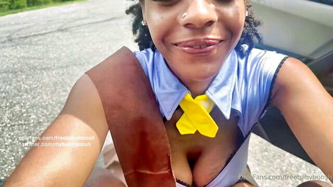 Curvy Black woman in sexy blue uniform with yellow tie, deep cleavage in car selfie