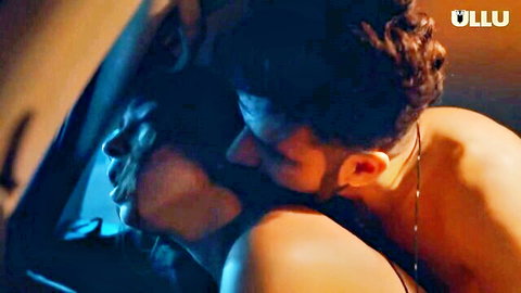 Passionate Indian couple kissing intensely in car backseat