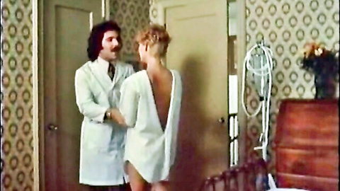 Retro 1982 foreplay scene: brunette doctor in lab coat embraces blonde in backless white dress