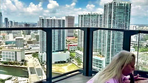 Blonde MILF on high-rise balcony with Miami skyline view