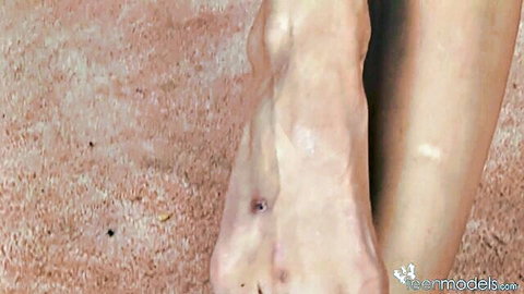 Close-up of pale bare foot with toes spread wide on sandy floor