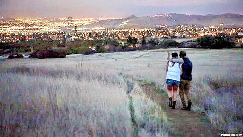 AJ Applegate and Ryan Madison walking hand-in-hand in grassy field at dusk