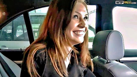 Smiling brunette in black top seated in luxury car backseat looking at camera