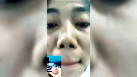 Blurry closeup of Asian girl smiling with finger touching her lips in amateur webcam tease