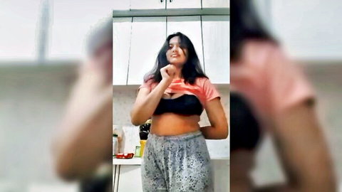 Sexy Indian girl teasing by lifting pink crop top to reveal black bra and curvy midriff