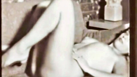 Vintage black-and-white stag film: nude woman lying with legs spread, hand on pussy