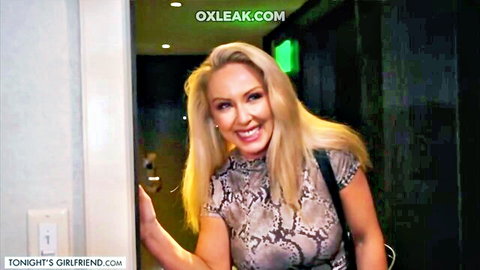 Blonde MILF Sadie Summers in tight snakeskin top, smiling in doorway