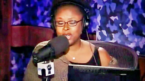 Ebony woman in glasses and headphones passionately speaking into microphone wearing BLM sweater