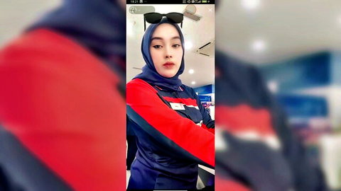 Young skinny Malaysian hijab girl in tight red tracksuit posing playfully in gym