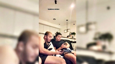 Blurry Asian couple cuddling baby on couch while watching phone homemade amateur