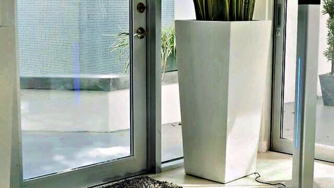 Empty modern glass door to patio with potted plants and blue lights, no nudity visible