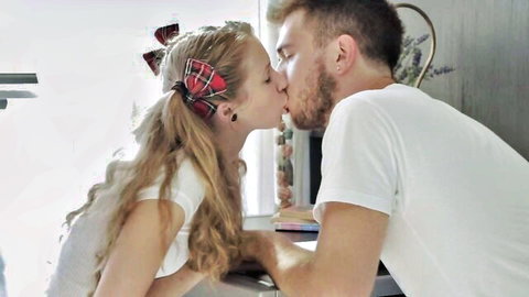 Petite blonde teen schoolgirl with plaid bow passionately kissing bearded guy over table