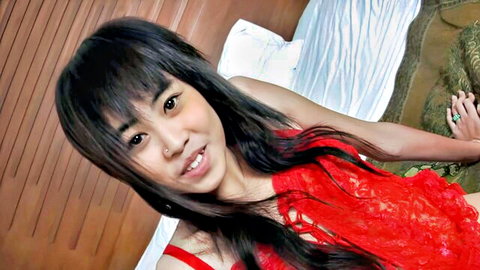 Beautiful Thai girl in red lace lingerie smiling seductively on bed