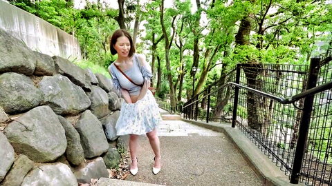 Smiling Japanese babe teasing upskirt lift outdoors in short floral skirt and heels