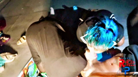 Blue-haired masked woman kneeling giving blowjob to man outdoors at night in homemade threesome