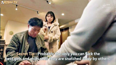 Japanese man sits as stepsister in coat stands nearby, teasing vibe