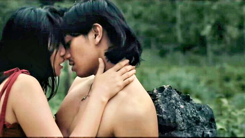 Passionate outdoor embrace of long-haired Asian couple kissing intimately