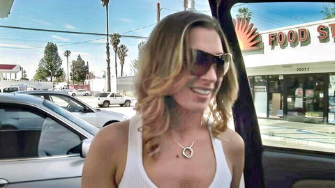 Devon Lee smiling in white tank top from car in sunny parking lot