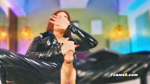 Redhead trans woman in shiny black latex suit masturbating her hard cock