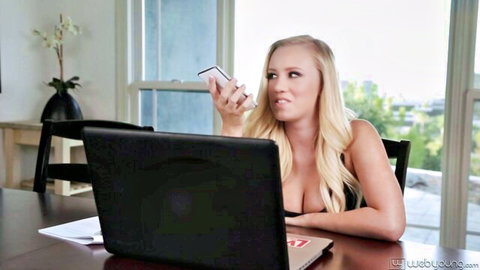 Surprised blonde babe with deep cleavage holding phone at desk
