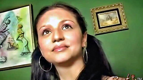Sexy brunette with pigtails and hoop earrings smiling seductively at camera