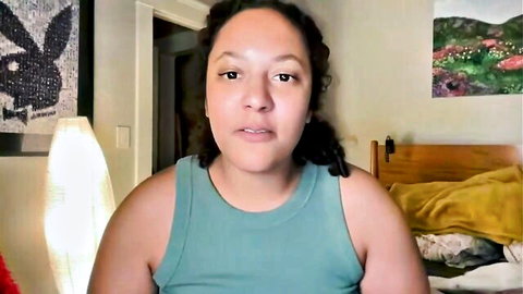 Dreamyriri in teal tank top, curly-haired Latina solo pose
